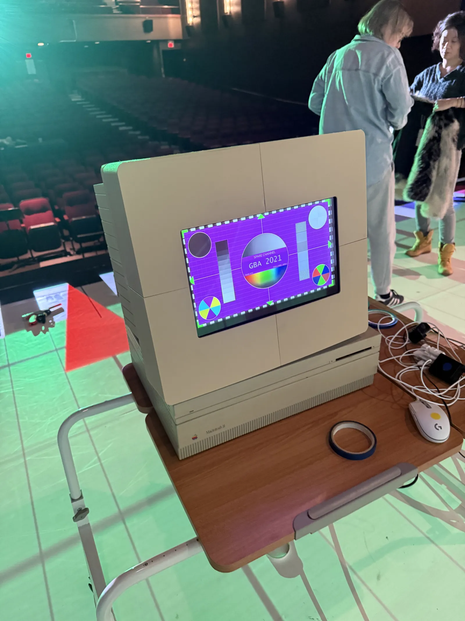 2021: the player’s screen in a case shaped like an Apple Macintosh II, showing a test pattern, on a stand on the stage