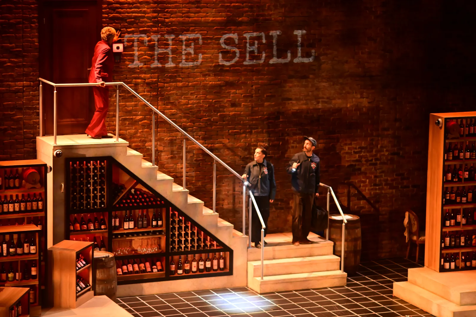 Heist: “The Sell” projected on the brick wall of the wine cellar, a woman in red at the top of the stairs