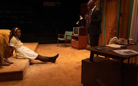 The Mountaintop: a woman in a maid’s uniform sits on the bed, a man in a suit stands by the desk, in a motel room