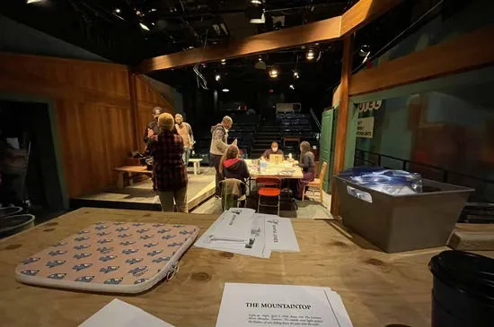 The Mountaintop: the company around a table on the set, seen across a worktable with scripts